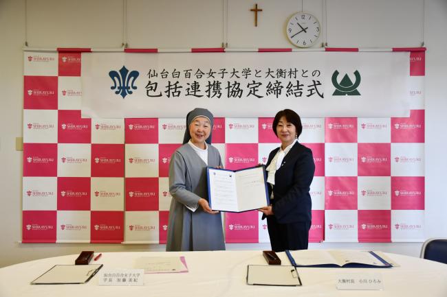 仙台白百合女子大学と大衡村との包括連携協定締結式で学長と村長が協定書を持つ写真